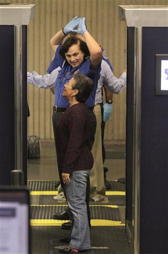 A female traveler, front, receives instruction from a Transportation Security Administration officer on the correct position for a full-body scan at Boston's Logan International Airport, Monday,