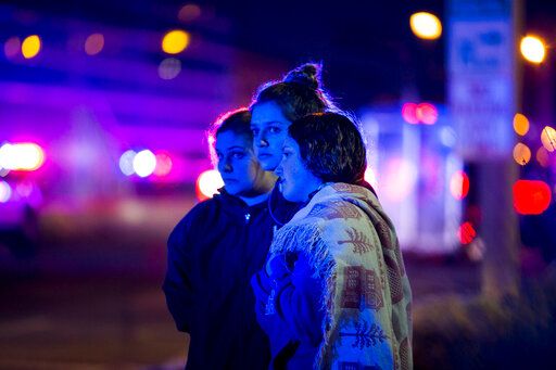 Aubrey Point, 14, from left, Lyndi Kenney, 16, and Natalie Roesslein,15, all from Oregon, watch a procession of law enforcement vehicles and the hearse carrying the body of slain McHenry County Sheriff's Deputy Jacob Keltner outside the Winnebago County Coroner's Office Friday, March 8, 2019, in Rockford, Ill. An Illinois man faces federal murder charges in the shooting death of the sheriff's deputy that led to an hourslong standoff with police along an interstate. (Scott P. Yates/Rockford Register Star via AP)