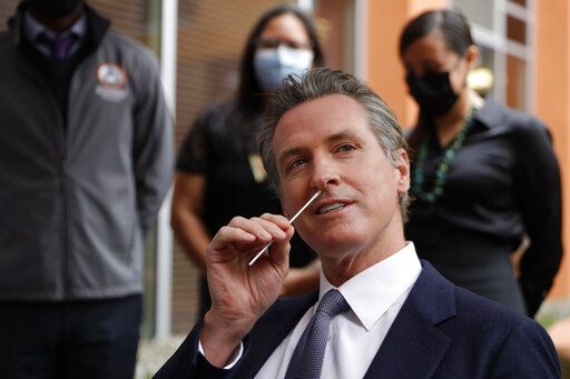 California Gov. Gavin Newsom gives himself a COVID-19 PCR test at the Native American Health Center in Oakland, Calif., on Wednesday, Dec. 22, 2021. California's roughly 2.5 million health care workers have until Feb. 1 to get a coronavirus vaccine booster shot or risk losing their jobs, Gov. Newsom announced Wednesday. (Jane Tyska/Bay Area News Group via AP)