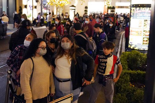 Visitors wear face masks while waiting to board a trolley at a shopping district Wednesday, Dec. 22, 2021, in Los Angeles.