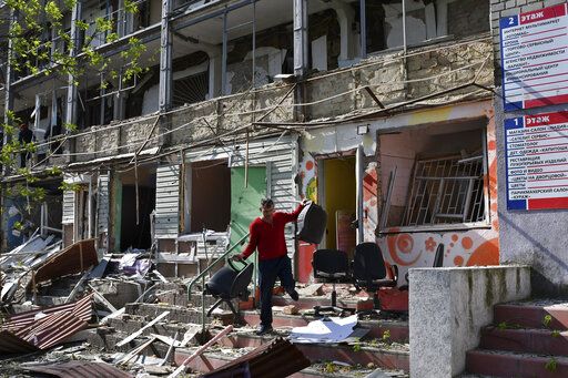A man carries chairs out of an office on a ground floor of an apartment building destroyed by night shelling in Kramatorsk, Ukraine, Thursday, May 5, 2022.