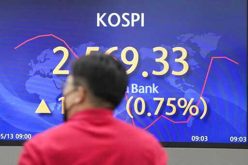 A currency trader walks by the screen showing the Korea Composite Stock Price Index (KOSPI) at a foreign exchange dealing room in Seoul, South Korea, Friday, May 13, 2022. Asian shares bounced back Friday from losses earlier in the week, shrugging off data showing U.S. wholesale prices soared 11% in April from a year earlier.