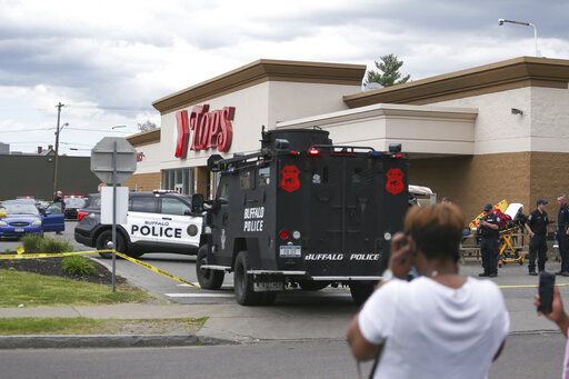 A crowd gathers as police investigate after a shooting at a supermarket on Saturday, May 14, 2022, in Buffalo, N.Y. Multiple people were shot  at the Tops Friendly Market.  Police have notified the public that the alleged shooter was in custody.