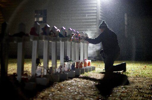 FILE - Frank Kulick, adjusts a display of wooden crosses, and a Jewish Star of David, representing the victims of the Sandy Hook Elementary School shooting, on his front lawn, Monday, Dec. 17, 2012, in Newtown, Conn.  After a weekend of gun violence in America, Saturday, May 14, 2022,  when shootings killed and wounded people grocery shopping, going to church and simply living their lives, the nation marked a milestone of 1 million deaths from COVID-19. The number, once unthinkable, is now a pedestrian reality in the United States, just as is the reality of the continuing epidemic of gun violence that kills tens of thousands of people a year.
