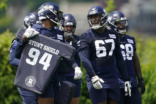 Seattle Seahawks tackle Charles Cross (67) talks with teammates during NFL football practice Monday, May 23, 2022, in Renton, Wash.