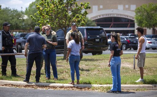 A law enforcement officer speaks with people outside Uvalde High School after shooting a was reported earlier in the day at Robb Elementary School, Tuesday, May 24, 2022, in Uvalde, Texas. (William Luther/The San Antonio Express-News via AP)