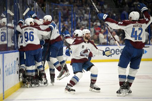Colorado Avalanche center Andrew Cogliano, center, and defenseman Josh Manson (42) celebrate the overtime goal by teammate center Nazem Kadri (91) in Game 4 of the NHL hockey Stanley Cup Finals against the Tampa Bay Lightning on Wednesday, June 22, 2022, in Tampa, Fla.