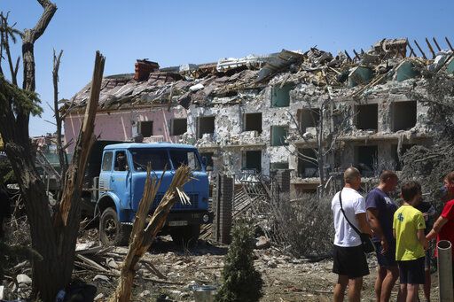 Local residents stand next to damaged residential building in the town of Serhiivka, located about 50 kilometers (31 miles) southwest of Odesa, Ukraine, Friday, July 1, 2022. Russian missile attacks on residential areas in a coastal town near the Ukrainian port city of Odesa early Friday killed at least 19 people, authorities reported, a day after Russian forces withdrew from a strategic Black Sea island.