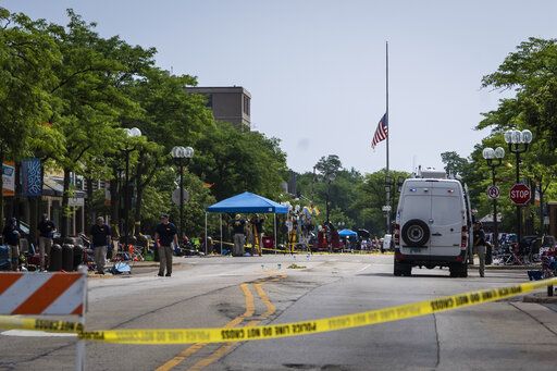 A flag hangs at half staff as members of the FBI's Evidence Response Team Unit investigate in downtown Highland Park, Ill., the day after a deadly mass shooting on Tuesday, July 5, 2022.   Police say the gunman who attacked an Independence Day parade in suburban Chicago fired more than 70 rounds with an AR-15-style gun.   (Ashlee Rezin /Chicago Sun-Times via AP)