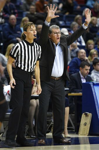 FILE - Connecticut head coach Geno Auriemma gestures to his team as official Dee Kantner, left, watches play during the second half an NCAA college basketball game against Central Florida, Tuesday, Jan. 9, 2018, in Storrs, Conn. As the NCAA examines various disparities across men's and women's sports, pressure is rising to pay referees equally throughout the regular season - and three top conferences told The Associated Press they plan to make changes.