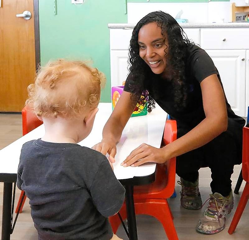 Teacher Marcye Meisinger interacts with a student as he draws a picture with markers at the Friendship House in Crystal Lake. Child care centers are struggling to find enough teachers to maintain operations.