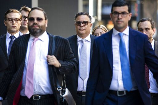 Flanked by attorneys, Derrel McDavid, center, walks into the Dirksen Federal Courthouse in Chicago as opening statements were expected to begin in R. Kelly's trial, Wednesday morning, Aug. 17, 2022. Two Kelly associates, Derrel McDavid and Milton Brown, are co-defendants. McDavid is accused of helping Kelly fix the 2008 trial, while Brown is charged with receiving child pornography. Like Kelly, they also have denied wrongdoing. (Ashlee Rezin/Chicago Sun-Times via AP)