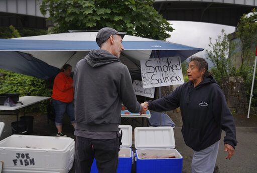 Jared Squires, left, buys fresh salmon from Christy Sampson in a parking lot near the Columbia River on Friday, June 17, 2022, in Cascade Locks, Ore.