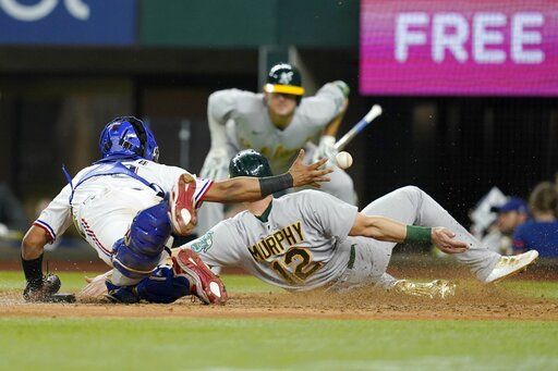 Texas Rangers catcher Meibrys Viloria loses the ball while trying to tag out Oakland Athletics' Sean Murphy (12) who scored on a single by Chad Pinder in the eighth inning of a baseball game, Wednesday, Aug. 17, 2022, in Arlington, Texas.
