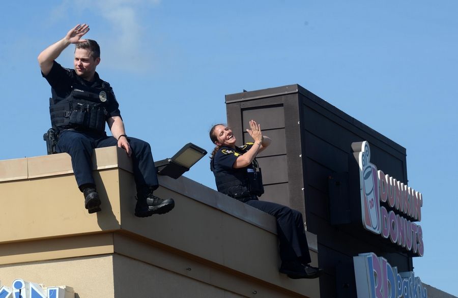 Detective James Cromley, left, and Sgt. Carly Gaba sit on the edge of the roof Friday as the Glenview Police Department participates in the statewide "Cop on a Rooftop" event at the Dunkin' Donuts at 1750 Milwaukee Ave. in Glenview.