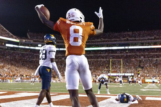 Texas wide receiver Xavier Worthy (8) celebrates a touchdown reception against West Virginia defensive back Jacolby Spells (28), linebacker Lance Dixon (5) and defensive back Aubrey Burks during the second half of an NCAA college football game Saturday, Oct. 1, 2022, in Austin, Texas.